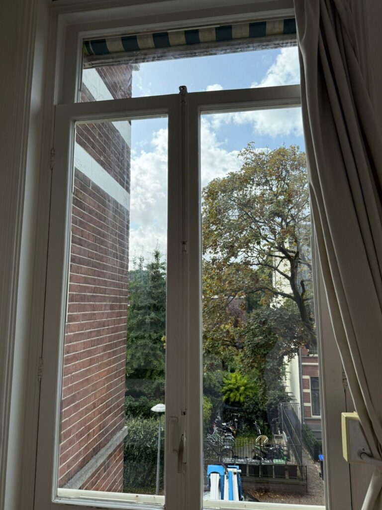 Hoog wit raam met bovenlicht, gezien vanuit de woning