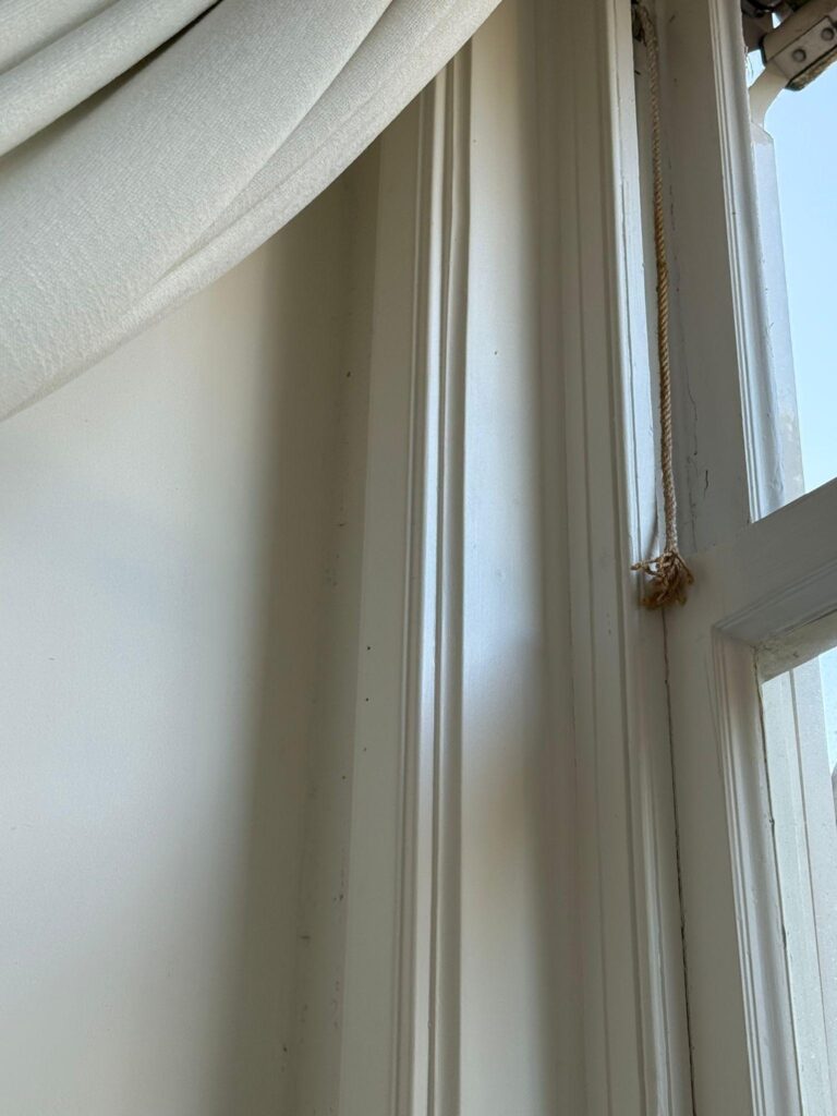 Detail van een wit houten raamkozijn aan de binnenzijde