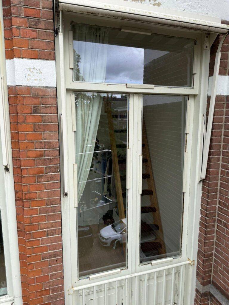 Bestaand wit houten raam met bovenlicht in een bakstenen gevel
