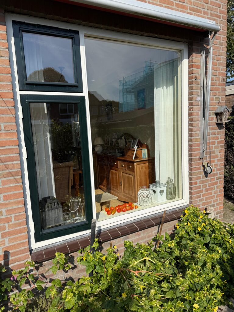 Groot woonkamerraam met zijramen in een bakstenen gevel