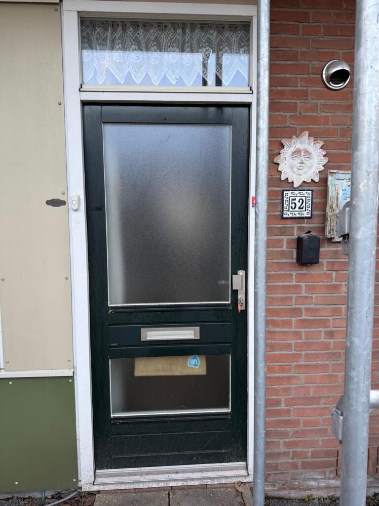 Donkergroene voordeur met ondoorzichtig glas en een bovenlicht