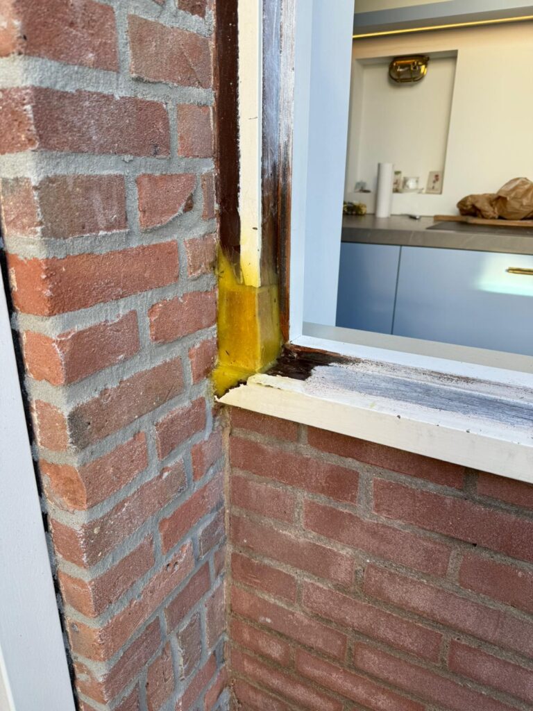 Detail van een houten raamsponning tijdens beglazingswerkzaamheden