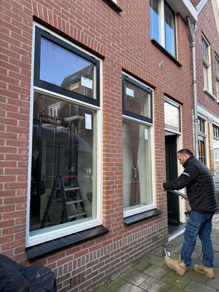 Glaszetter werkt aan een raam in een bakstenen gevel
