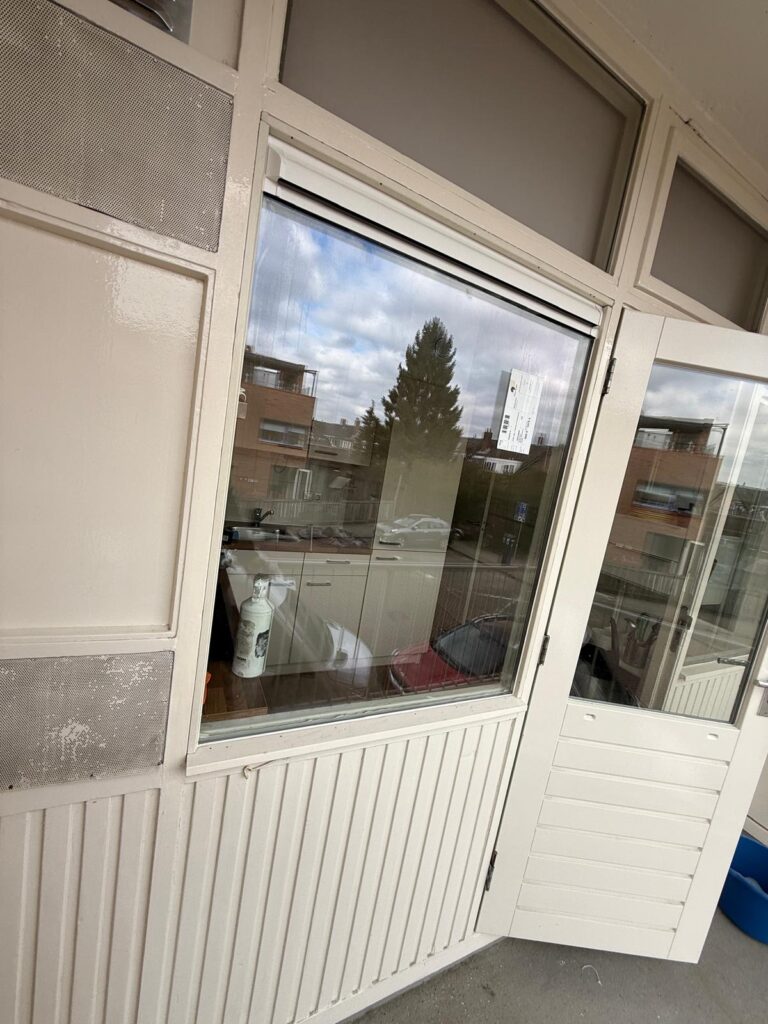 Beglazing in een witte kozijnconstructie met deur en bovenlichten